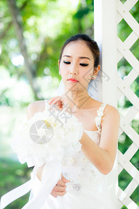 在婚礼当天美丽的年轻女子穿着白裙在花园里公的女肖像选择焦点图片