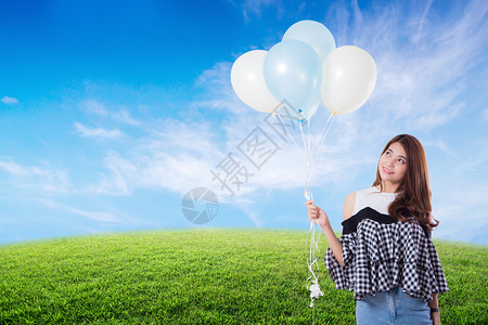 年轻女子在草原夏天带着自由生活方式的概念拿着气球图片