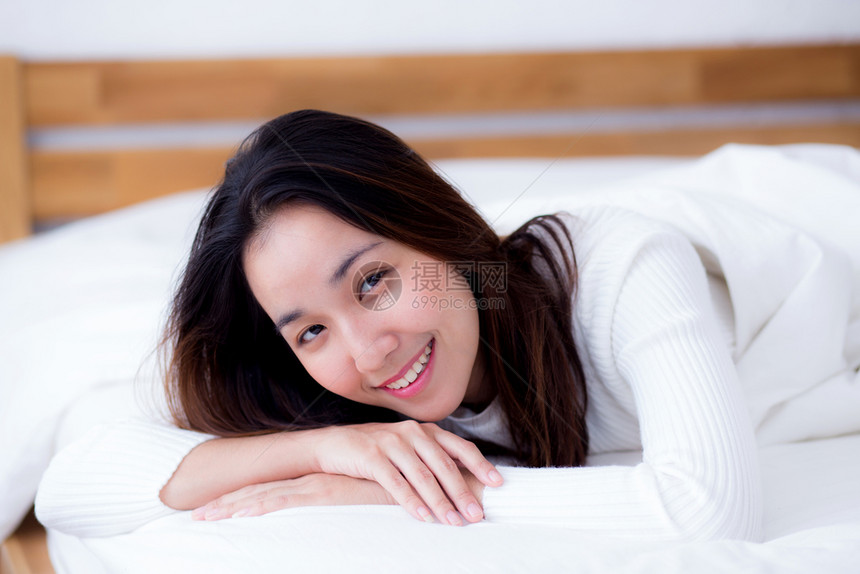美丽的女人微笑着肖像在睡觉和躺床上后清晨醒来图片