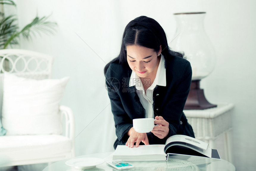 年轻女商人坐在咖啡店和阅读书桌前图片