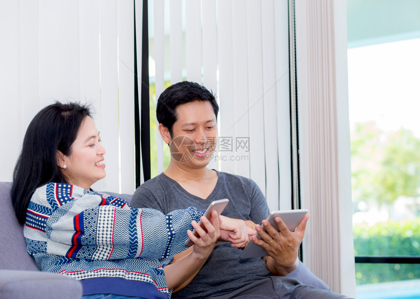 两个朋友用多台设备连线坐在室内客厅的沙发上聊天通信概念图片