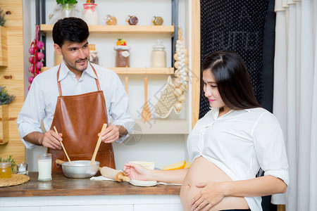 快乐的丈夫和怀孕妻子在厨房亚洲男人在家中厨房做饭快乐的家庭概念图片