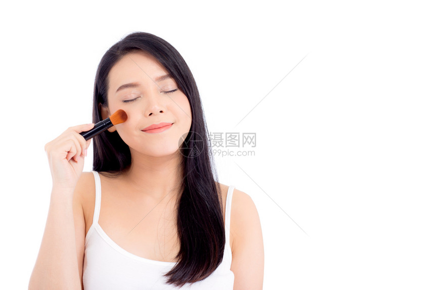 美貌的亚裔女在申请时用白色背景上孤立的脸颊刷子来弥补图片