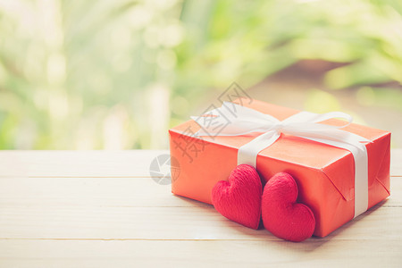 红礼盒和心形在木质桌顶上自然绿色模糊布基背景情人节概念图片