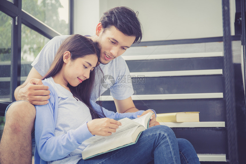 双胞胎的英俊男子和美丽的女人阅读书在家里微笑男朋友和女一起活动休闲教育概念图片