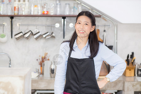 美丽的年轻咖啡师肖像亚裔女是一名员工站在柜台咖啡店服务概念图片