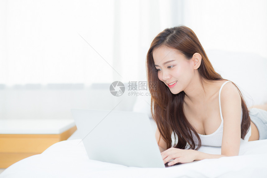 在卧室用笔记本电脑躺在床上休息和放松的美丽亚洲年轻妇女自由职业有女孩工作笔记本有通信概念图片