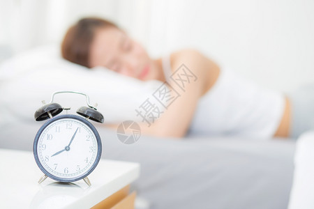 清晨的闭门闹钟和美丽的亚洲年轻女醒来后用闹钟放松和生活方式概念睡觉图片