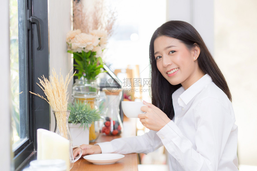 美丽的年轻女在咖啡馆喝早上微笑女孩坐在咖啡店吃早餐图片