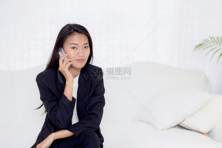 美丽的年轻女士在客厅讲电话和微笑女商人坐在沙发上女商人打电话通信概念图片
