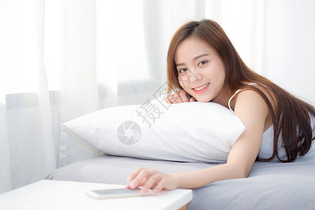 美丽的年轻女士手关闭警报按呼叫移动电话醒来后睡觉休息放松在卧室的早晨图片