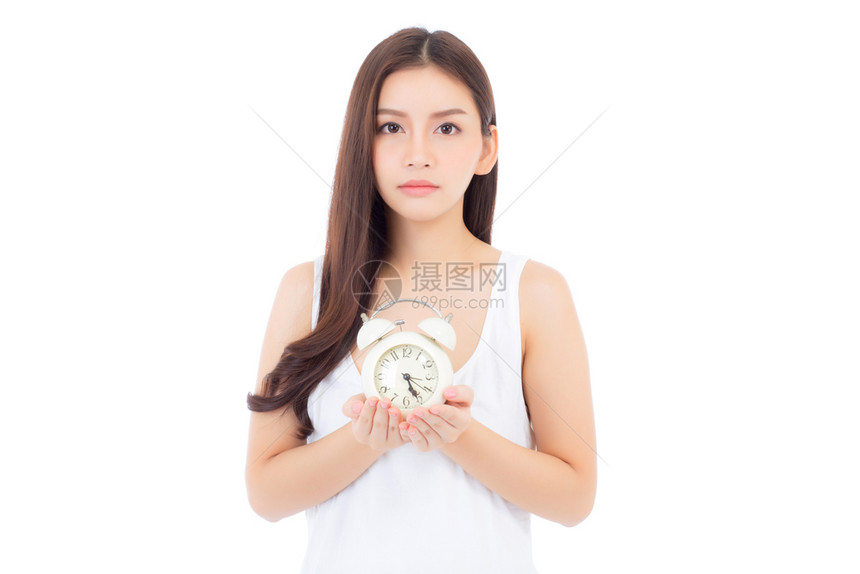 美丽的亚洲年轻女拿着闹钟醒来时的肖像与白种背景隔离的女孩时间与最后期限的概念图片