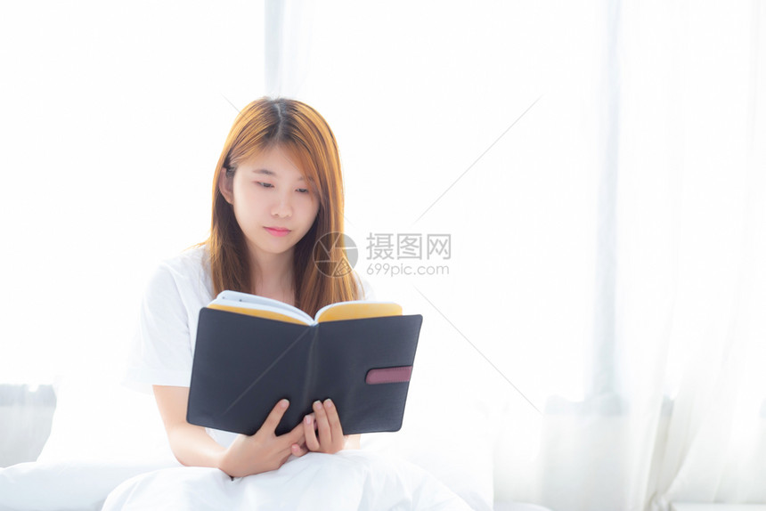 美丽的肖像年轻亚洲女放松坐在家里卧室的阅读书女孩学习文教育和生活方式概念图片