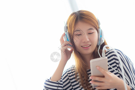 美丽的亚洲年轻女坐在卧室里享受耳机闲暇和技术概念的轻松女孩图片