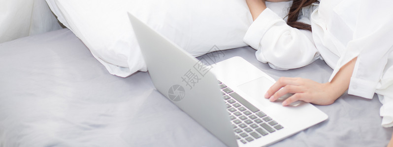 Banner网站的美丽年轻女膝上型电脑躺在卧室睡觉休息背景图片