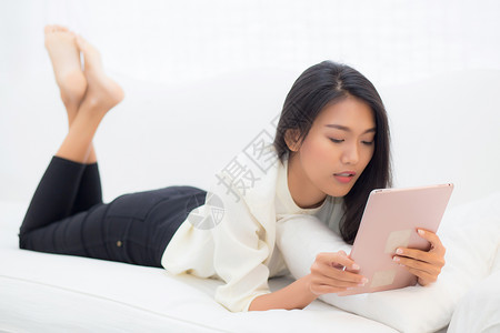 使用数字平板电脑在家里躺着沙发女孩满足社交网络商业流概念图片