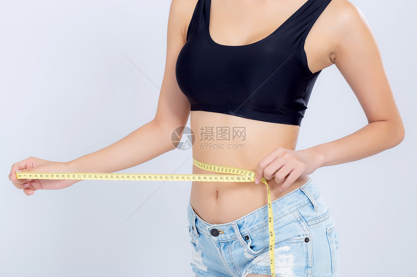 女孩吃紧了作为饮食长着腰部与白色背景的体重隔绝女孩用胶带测量健康和概念丧失了纤维素和卡路里图片