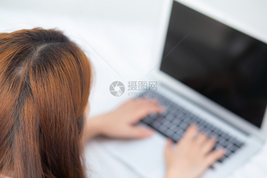 利用笔记本电脑在卧室闲暇女孩在线工作使用笔记本自由职业者商概念图片