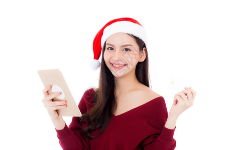 美丽的亚洲年轻女子用信卡购物在圣诞节日持有平板电脑图片