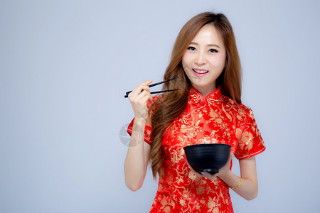 美丽的肖像年轻亚洲女穿着红青山拿筷子和碗孤立在白色背景新年假期的概念图片