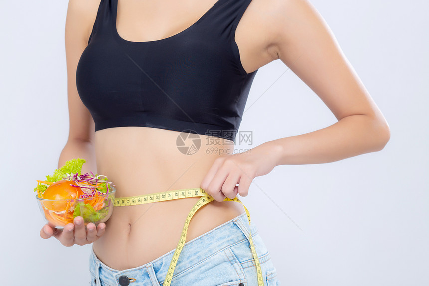 近身穿紧衣的妇女持有沙拉蔬菜食品在白种背景上为体重而测量腰部用胶带测量保健或康概念食用纤维素损失的女孩饮食图片