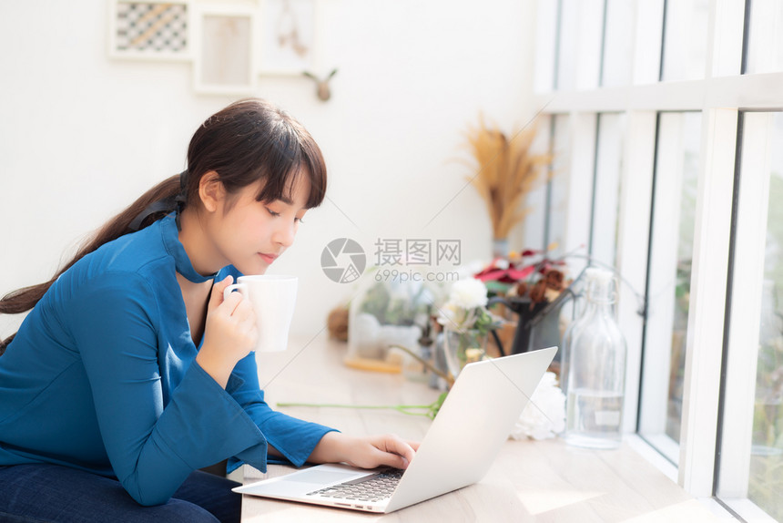 美丽的年轻自由职业女利用笔记本和喝咖啡商业与生活方式概念与专业的Asia女孩一起在办公咖啡厅微笑工作并使用笔记本电脑和图片