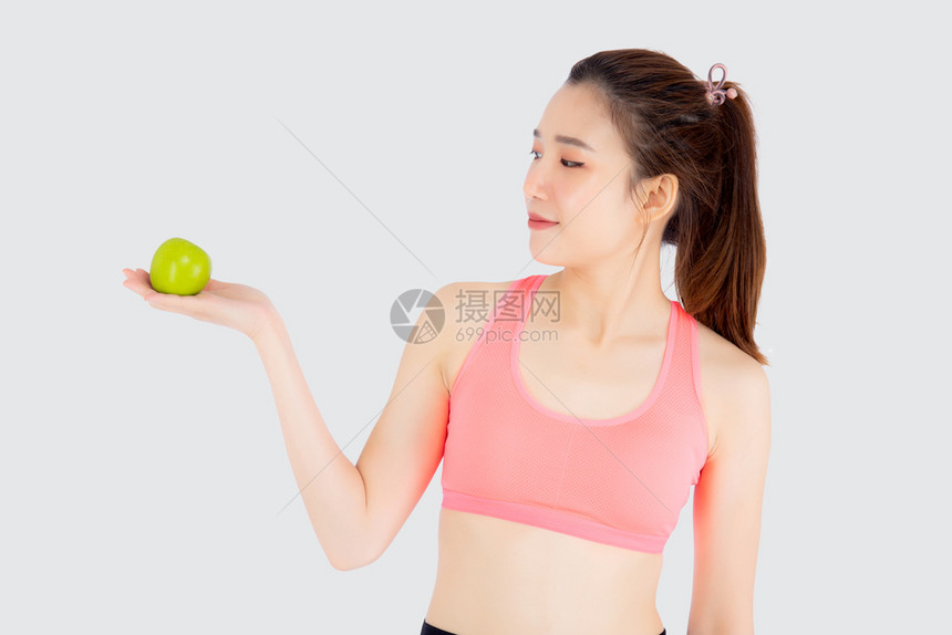 年轻穿着运动服满足和持绿苹果孤立在白色背景上女孩有形状和健康为适应概念而锻炼的美丽肖像图片