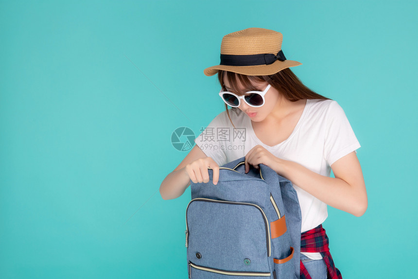 年轻女美丽肖像戴着太阳镜微笑的帽子开着背包旅行暑假期孤立的蓝色背景旅游快乐的Asia女孩有信心包图片