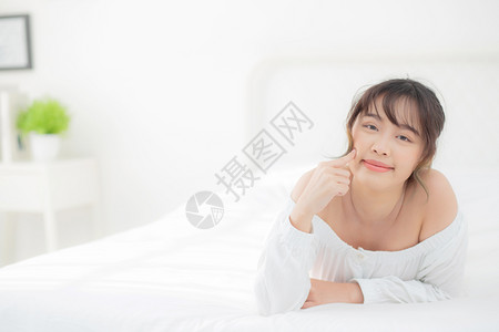 美貌丽的年轻女微笑早上在卧室醒来健康美貌女孩躺在皮肤上背景图片
