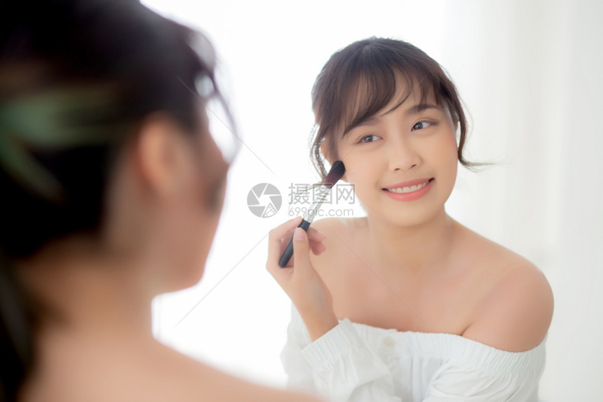 美容肖像年轻的女微笑面朝镜子化妆在卧室刷脸美丽的女孩抱着脸红皮肤护理和化妆品概念图片