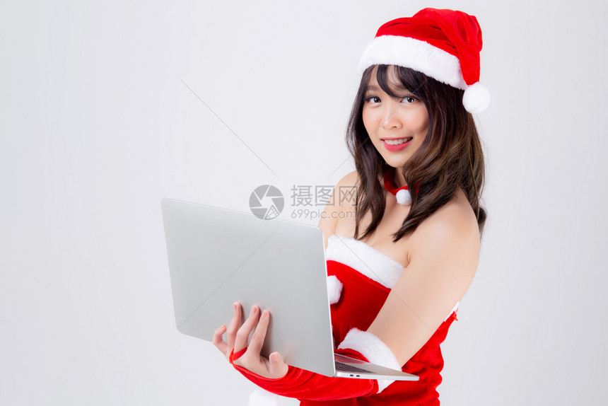 在圣诞节日使用笔记本电脑与白人背景隔绝展示Asia女孩拿着笔记本在Xmas日庆祝图片