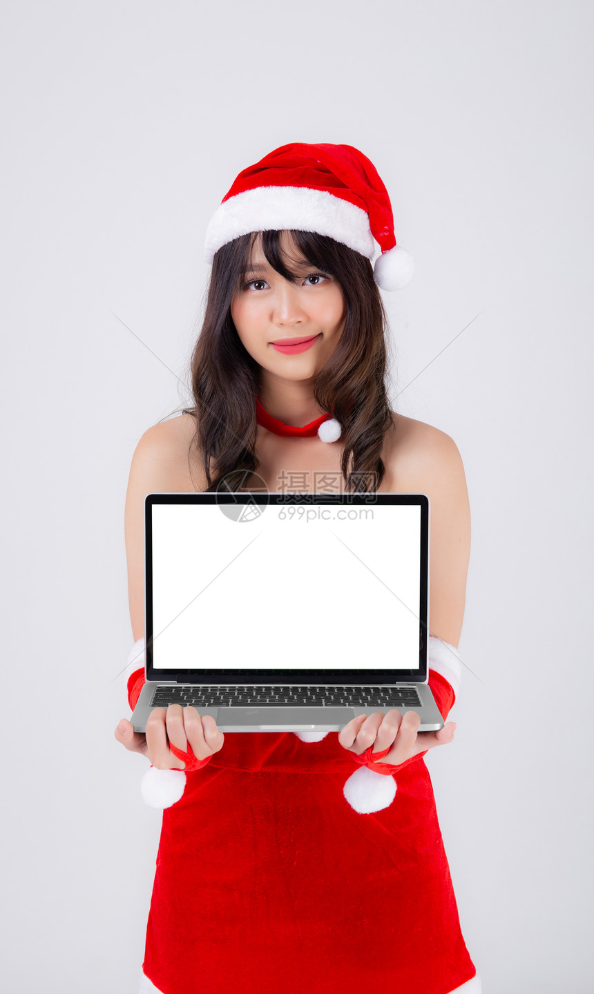 圣诞假时展示笔记本电脑却与白人背景隔绝美貌女孩拿着笔记本用于庆祝圣诞节或新年图片