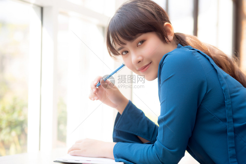 年轻女作家在笔记本或日上微笑着思考想写快乐Asia女孩的生活方式是学女规划工作教育和商业概念图片