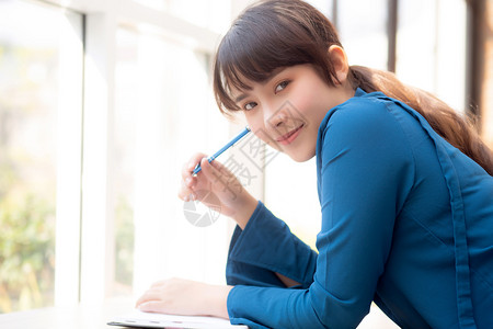 年轻女作家在笔记本或日上微笑着思考想写快乐Asia女孩的生活方式是学女规划工作教育和商业概念背景