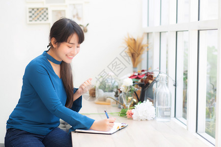 美丽的肖像亚洲女作家兴奋地写在笔记本或日记上与成功和快乐生活方式亚洲女孩是学生女计划工作教育和商业理念背景