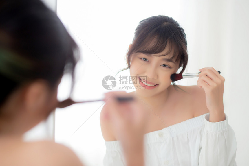 美容肖像年轻的女微笑面朝镜子化妆在卧室刷脸美丽的女孩抱着脸红皮肤护理和化妆品概念图片