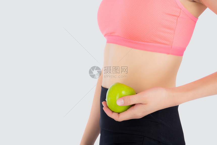 穿着运动服的美丽年轻女满足了身穿运动服并持有孤立在白色背景上的绿苹果女孩有形状和健康运动符合概念图片