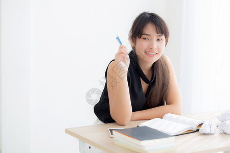 美丽的亚洲女作家在笔记本日上微笑的思考想法写作并计划在办公桌工作Asia女孩的生活方式在成功教育和商业概念方面受到启发背景