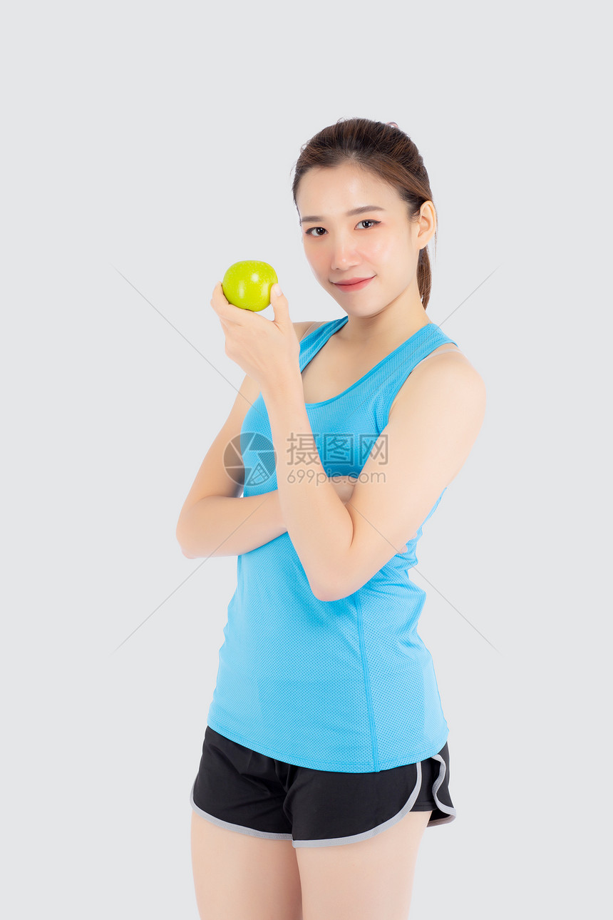 年轻穿着运动服满足和持绿苹果孤立在白色背景上女孩有形状和健康为适应概念而锻炼的美丽肖像图片