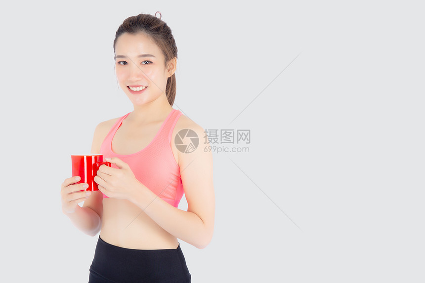 运动结束后美丽的年轻女在运动中锻炼后从玻璃中喝饮用水供白种背景的饥渴者喝锻炼后的女孩喝咖啡或茶图片