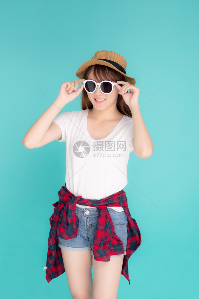 年轻的女戴着帽子拿太阳镜满怀信心地享受暑假旅行图片