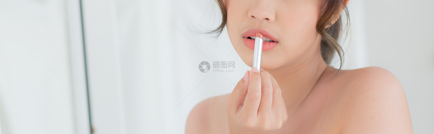 美的肖像年轻女看着镜子在房间里涂化妆口红美的嘴唇像女孩化妆时装生活方式和保健概念横幅网站图片