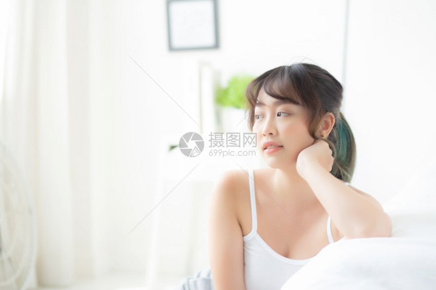 美貌丽的年轻女微笑早上起床时醒来健康美貌女孩在床上快乐地躺皮肤上卧室化妆品生活方式和放松概念图片