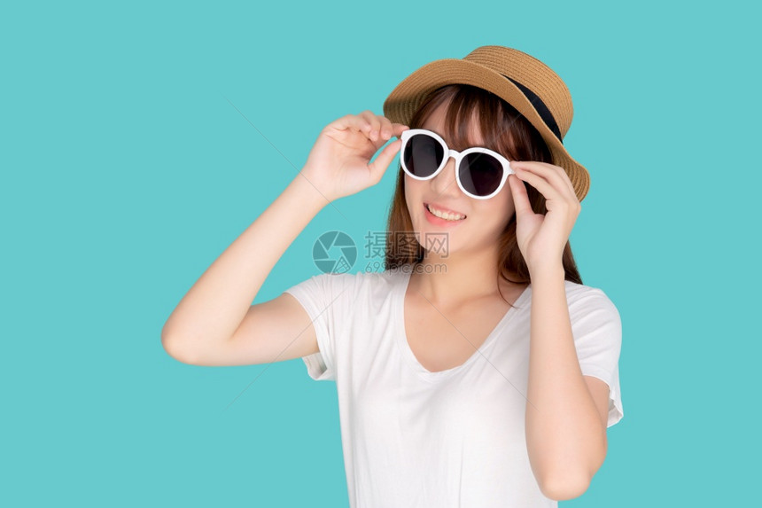年轻的女戴着帽子拿太阳镜满怀信心地享受暑假旅行图片