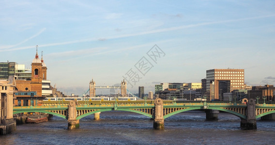 伦敦日落时泰晤士河的景象南华克桥位于前台和塔的背景图片