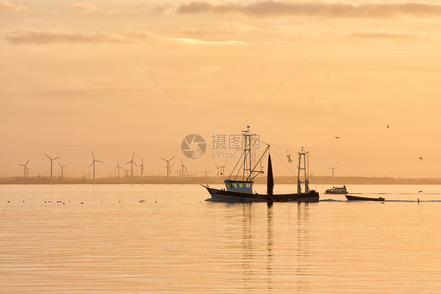 日落在荷兰海面上空渔船返回海平线上的港口和风涡轮鱼图片