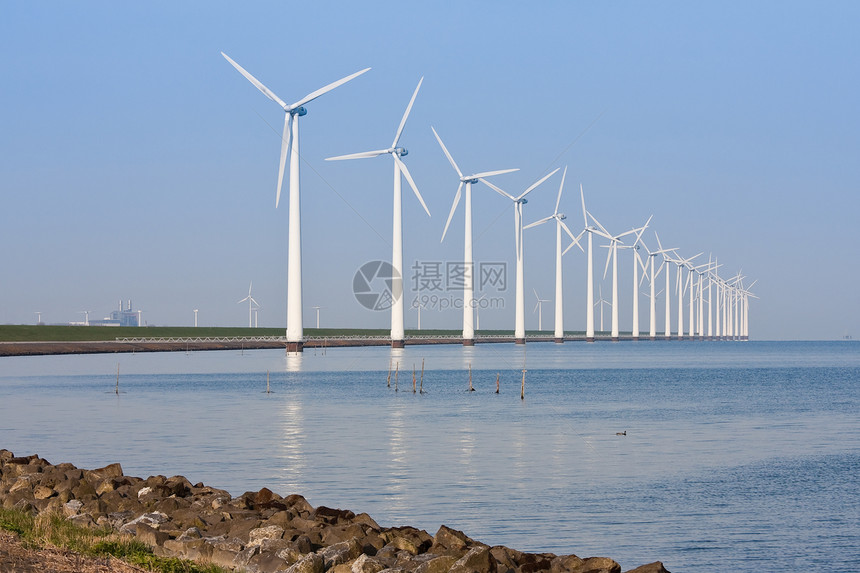 沿海岸线的荷兰风车在平静的海中照耀图片