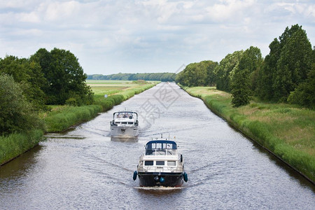 两艘游艇在一条直的荷兰运河上航行图片