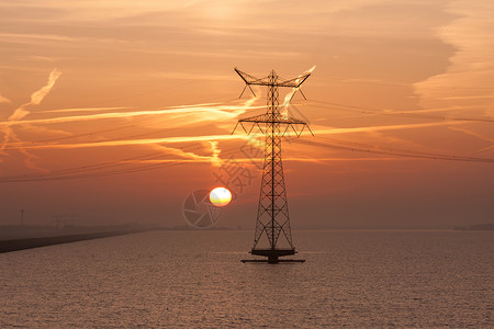 水电线日出在荷兰海面上空与电流高柱的轮廓背景