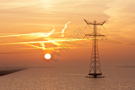 日出在荷兰海面上空与电流高柱的轮廓图片